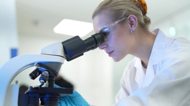 A pathologist in a hospital lab examines a stained tissue specimen under a microscope, identifying cellular abnormalities to provide a definitive diagnosis for a patient's condition.