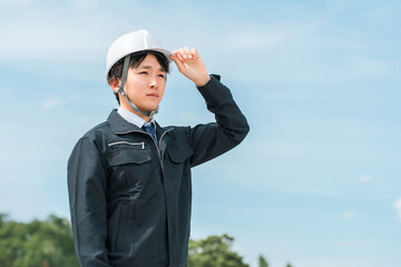 公園・森林にいる作業着姿の若いアジア人男性（林業・電気工事士・保守・点検）
