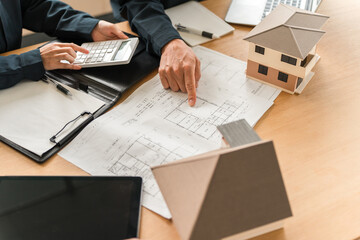 Businessmen having a meeting in front of a house model and blueprints
