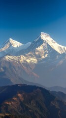 Majestic snow capped mountains bathed in golden sunlight under a vibrant clear blue sky, a breathtaking natural landscape.