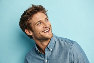 Obraz premium Cheerful young man smiling against a light blue background, exuding positivity and confidence