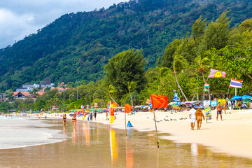 Patong Beach Phuket with people promenade sun loungers parasols Thailand.
