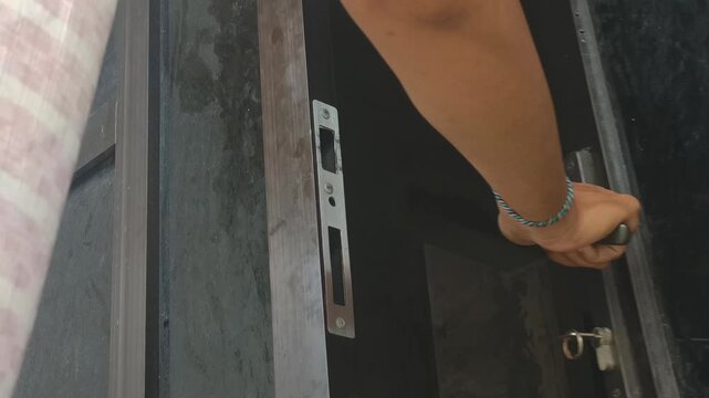 Close up of a man's hand turning a key to open the locked door of a house. opened the locked aluminum door. 