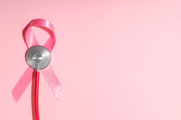 Stethoscope with a pink ribbon placed on a pink background