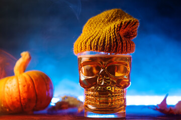 A skull beer glass with an autumn hat on a blue background. Halloween drink idea for a bar or party.