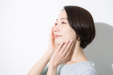 頬に手を当てる笑顔の女性のクローズアップ　美容やビューティーなどのイメージ