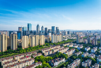 Naklejka premium Aerial view of a modern residential district with the commercial city skyline under a clear blue sky in Suzhou. Urban development and real estate background.