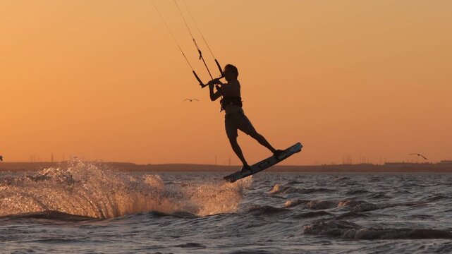 Experienced kitesurfer enjoying powerful ride across ocean during sunset golden light with board slicing water creating spray symbol of adventure freedom extreme sports lifestyle motivation