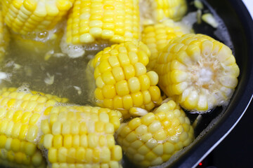 Corn pieces boiling in hot water inside a pan.