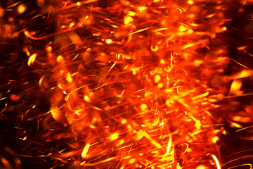 Fiery orange and yellow spark trails creating a vibrant, energetic pattern against a dark backdrop.