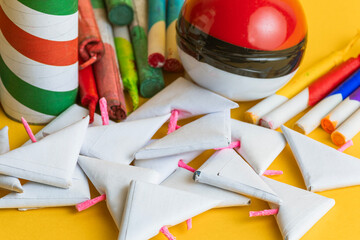 Close-up of a mix of firecrackers, rockets, and paper explosives on a vibrant yellow background, representing a festive celebration.