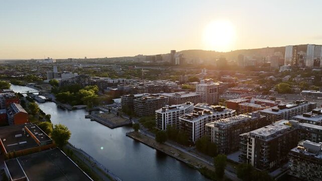 Aerial view of modern waterfront district with high-rise buildings and riverside paths, Montreal twilight skyline. g.