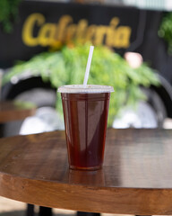 Vaso de café frío para llevar sobre mesa de madera en cafetería al aire libre