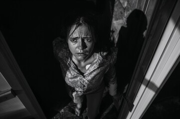 Woman stepping outside with tears looking distressed in a doorway  