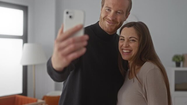 Man and woman joyously taking selfie with ultrasound photo in bright home showcasing pregnancy announcement and new family beginnings.
