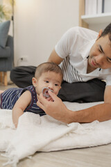 Obraz premium A father spends quality time with his baby, playing and bonding through gentle care and fun moments on a soft mat. The baby explores tummy time and pacifier use with support.