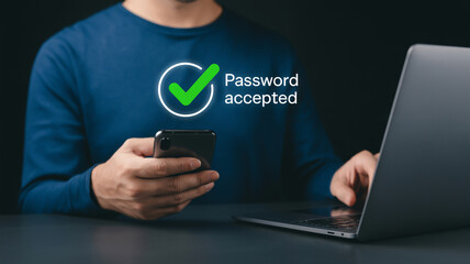 A man is using a laptop and a phone with a password accepted message