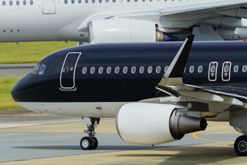 Close-up view of a commercial airplane cockpit and nose section at an airport. A pilot is preparing for flight, representing the aviation and travel industry.
