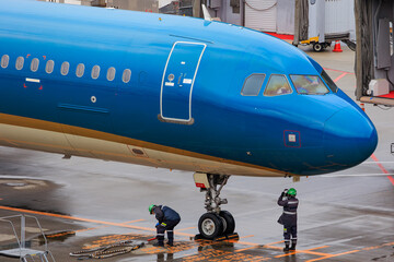 Close-up view of a commercial airplane cockpit and nose section at an airport. A pilot is preparing for flight, representing the aviation and travel industry.