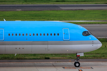 Close-up view of a commercial airplane cockpit and nose section at an airport. A pilot is preparing for flight, representing the aviation and travel industry.