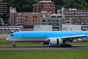 Close-up view of a commercial airplane cockpit and nose section at an airport. A pilot is preparing for flight, representing the aviation and travel industry.