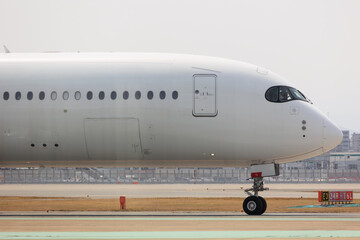 Close-up view of a commercial airplane cockpit and nose section at an airport. A pilot is preparing for flight, representing the aviation and travel industry.