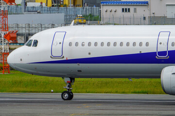 Close-up view of a commercial airplane cockpit and nose section at an airport. A pilot is preparing for flight, representing the aviation and travel industry.