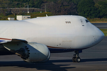 Close-up view of a commercial airplane cockpit and nose section at an airport. A pilot is preparing for flight, representing the aviation and travel industry.