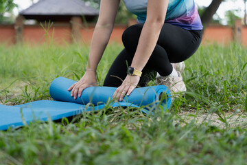 Woman Rolling Up Yoga Mat After Exercising in Park.