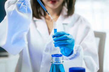 Fototapeta premium An Asian female scientist carefully analyzes microscopic samples and chemical solutions in a modern laboratory, conducting biology, microbiology, pharmaceutical, and medical research with precision