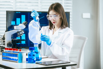 An Asian female scientist carefully analyzes microscopic samples and chemical solutions in a modern...