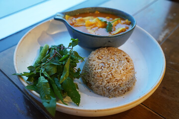 Close up brown rice served with sour Thai soup and fresh vegetable