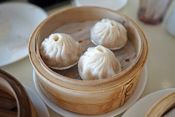 Close up 'Xiao Long Bao' Chinese Dim Sum, broth-filled Shanghainese steamed pork dumplings served in wooden basket container