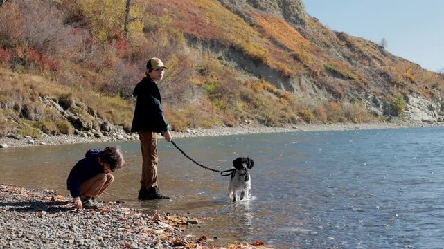 Children and their dog having fun by the river on sunny day in Autumn