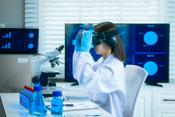 An Asian female scientist in a modern lab interacts with 3D holographic data using VR/MR headset,...