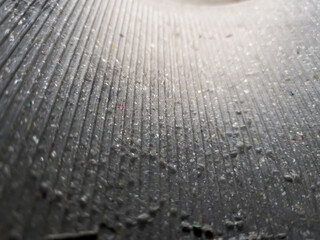 Close-up of abstract surface with vertical ridges and scattered dust particles. Ideal for texture studies, industrial design, or minimalist backgrounds.