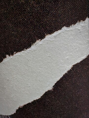 Close-up of torn paper edge with fibrous texture placed on a dark speckled background. Ideal for abstract design, texture studies, or creative compositions.