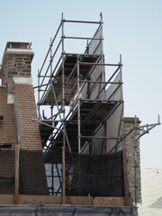 Construction scaffolding on stone building under clear blue sky
