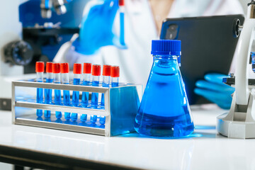 An Asian female scientist carefully analyzes microscopic samples and chemical solutions in a modern laboratory, conducting biology, microbiology, pharmaceutical, and medical research with precision