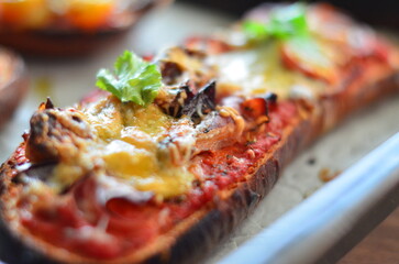 Close-up of a freshly baked zapiekanka baguette topped with vegetables, tomatoes, and fresh herbs, showcasing vibrant colors and appetizing textures, perfect for food, culinary, and gourmet projects