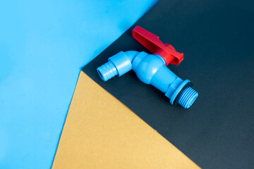 Plastic Water Tap with Red Handle on Abstract Geometric Color Block Background