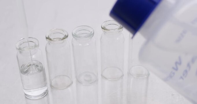 Filling glass test tubes with transparent buffer using a thin and long pipette.