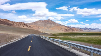 A long asphalt road extending through a scenic mountainous area