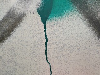 Colorful Abstract Wall Pattern. A striking contrast of colors with a central crack creating a focal point. The texture is highlighted by teal and gray tones, adding depth.