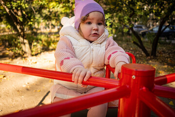 A cheerful child rides on a vibrant carousel in a lively park surrounded by colorful autumn leaves. The sun shines brightly as joyful laughter fills the air.