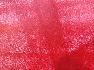 Colorful abstract wall pattern. A close-up view of a textured red surface showcasing various shades and patterns. The image has a tactile quality with a blend of lighter and darker red tones.