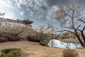 Captured this serene view of Hwaseong Fortress' Banghwasuryujeong in March. The calm pond and traditional architecture under a cloudy sky are just stunning. A perfect spring moment!
