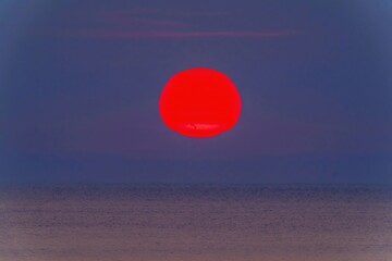 屏風岩展望台から見た日本海に沈むゆがんだ形の夕日の情景