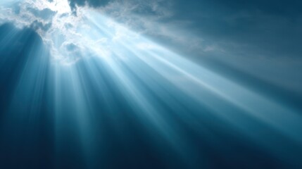 Ethereal rays of light pierce through dark clouds, creating a serene and uplifting atmosphere in a tranquil blue sky.