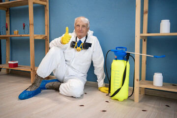 Disinfection worker from pest control service in protective suit and respirator mask sitting near...